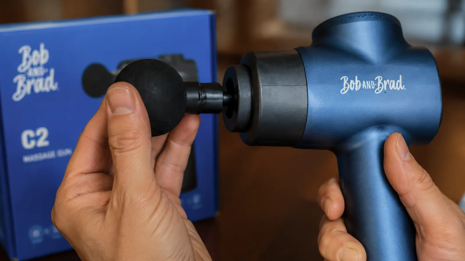 Close-up of the BOB AND BRAD C2 massage gun attachment socket being fitted with the ball head by a hand