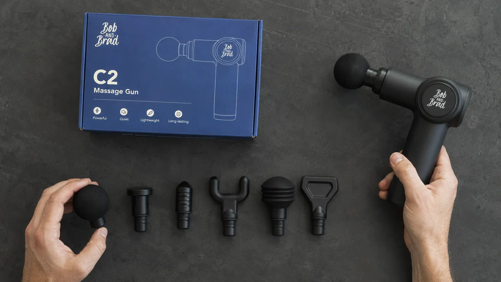 Close-up of the six attachment heads included with the BOB AND BRAD C2 massage gun laid out on a dark surface