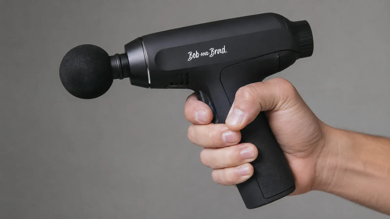 Hand holding the BOB AND BRAD C2 massage gun showing its ergonomic grip angle