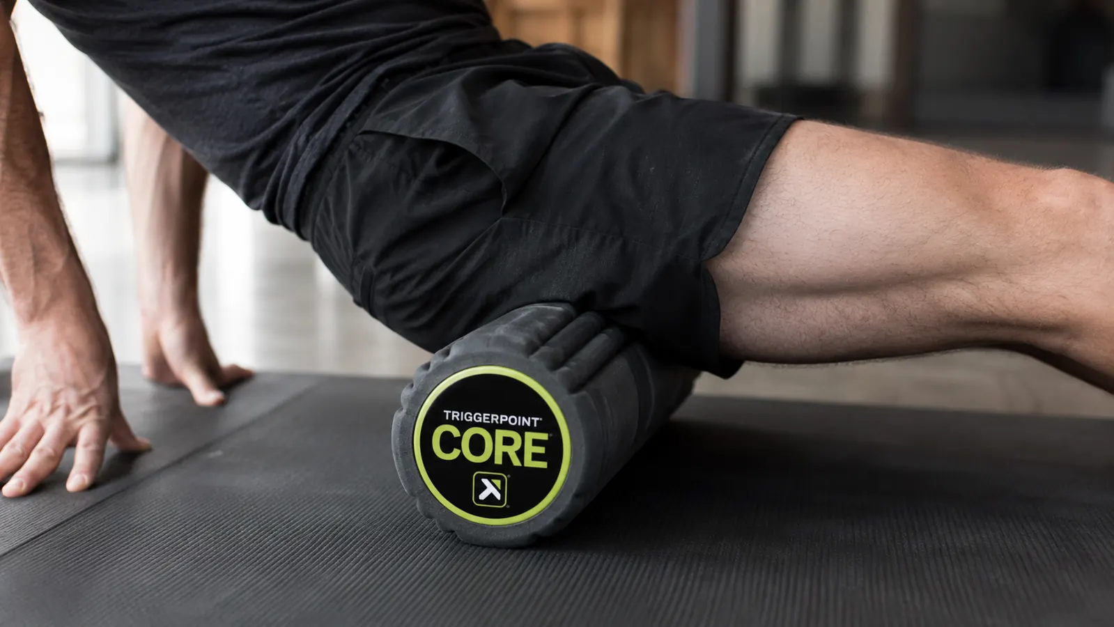 TriggerPoint CORE foam roller positioned under a person's outer thigh for IT band work