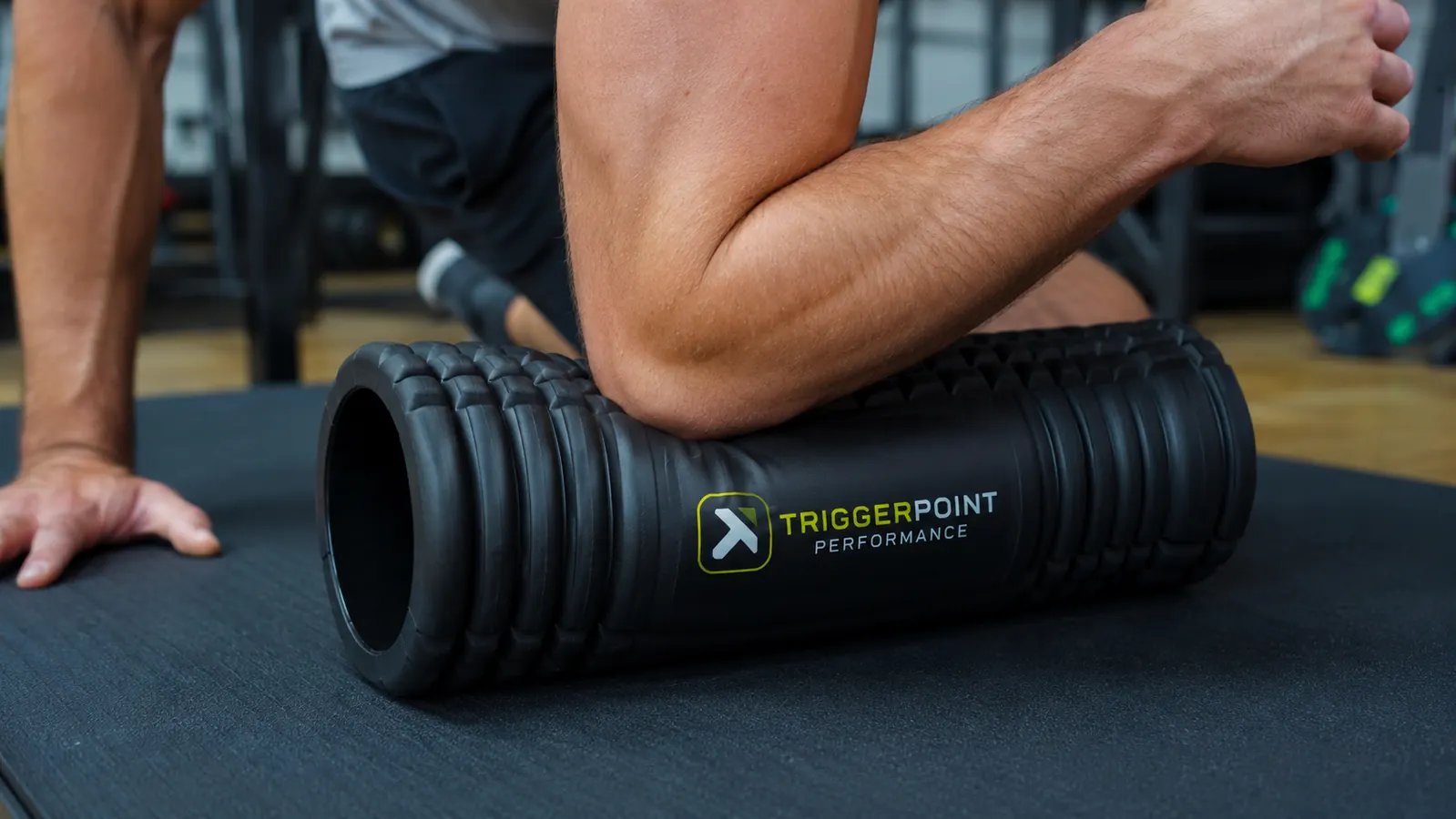 Man pressing forearm into the TriggerPoint CORE foam roller to demonstrate compression feel