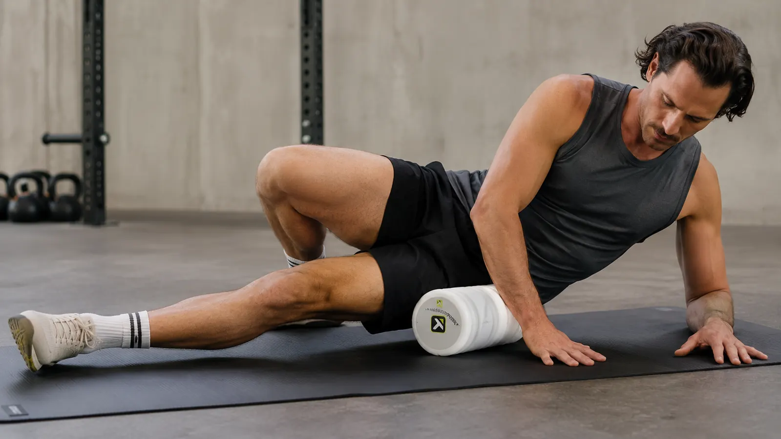Person using the TriggerPoint CORE foam roller on their quad on a gym mat