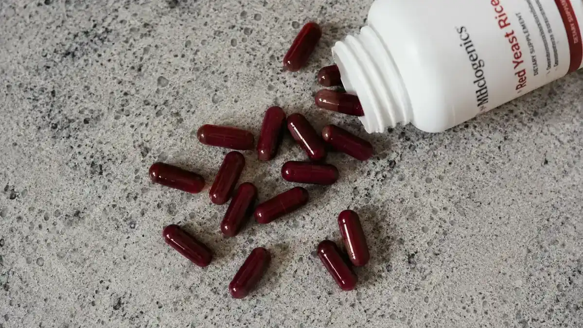 Open capsule jar showing dark red capsules with a measuring scoop on a granite countertop
